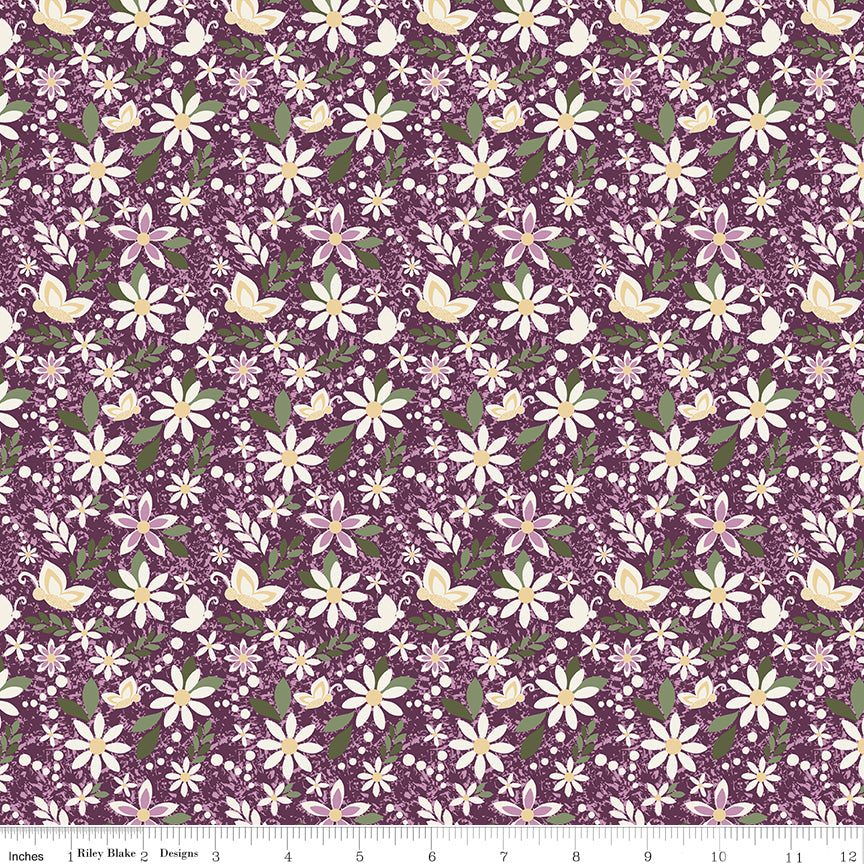 Juju's Petals Dance Purple floral quilting fabric shown with a ruler for scale, featuring cream and pink daisies with green foliage on a purple background.