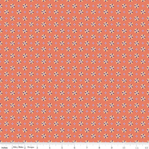 Juju's Petals Calico Orange floral fabric shown with a ruler for scale, featuring rows of colorful small flowers on a coral-orange background.