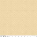 Juju's Petals Yellow Dots fabric shown with a ruler for scale, featuring tiny scattered white dots on a buttery yellow background.